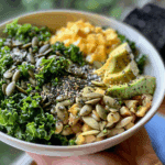 Close-up of Erewhon Kale Salad in a clean white bowl with avocado, seeds, kale, and diced vegetables.